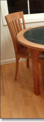 Extra dining chairs work with the kitchen table, designed by J.T. John in cherry and soapstone.