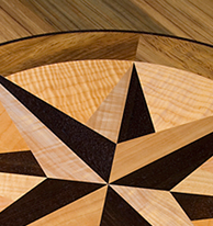 This compass rose out of solid wood lies in the top of an oval table J.T. John designed for a yacht based in Washington. It features Peruvian walnut, quilted maple, and “figured” teak, all in a field of teak.